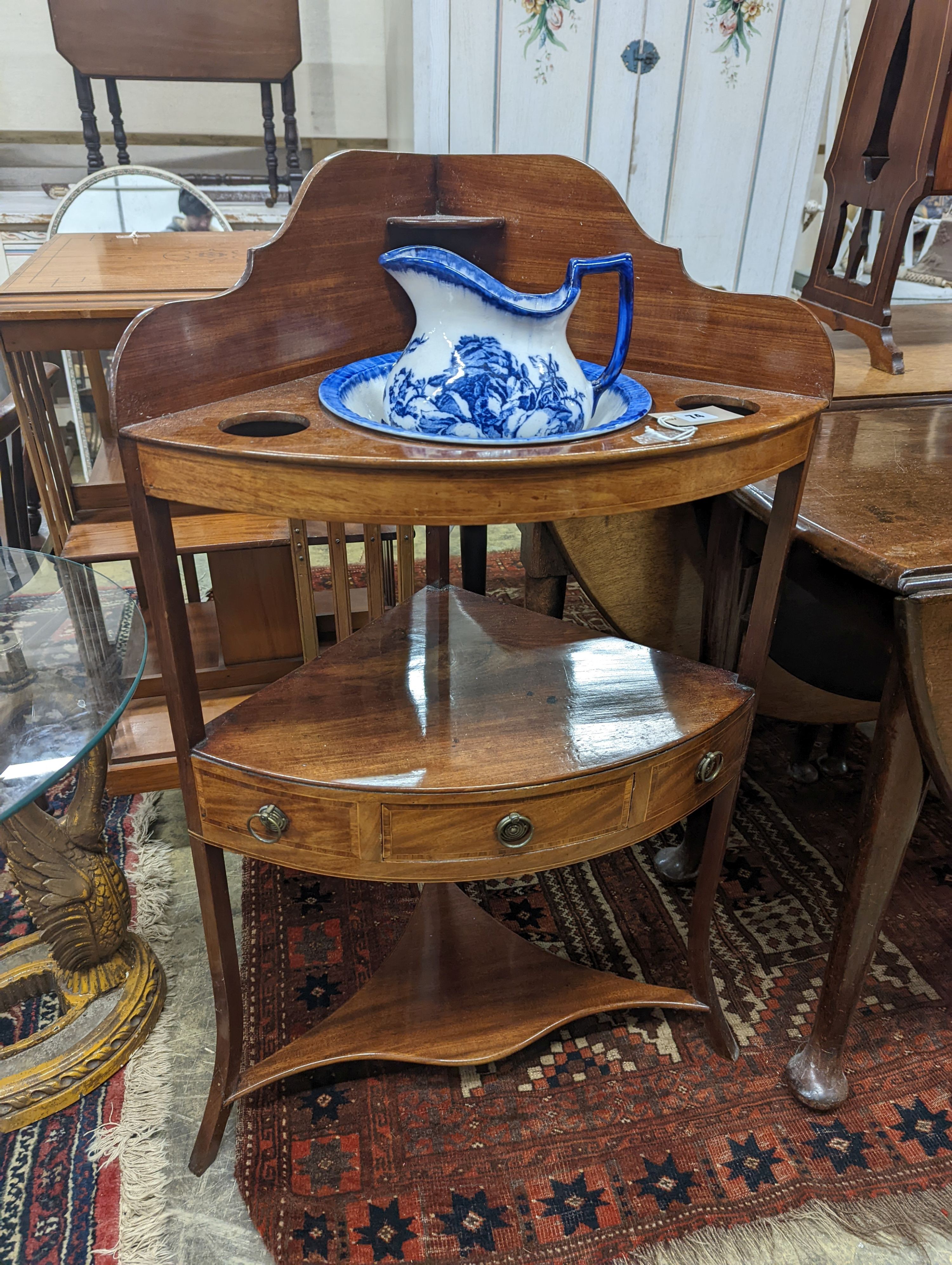 A George III mahogany bow front three tier corner washstand, width 58cm, depth 38cm, height 99cm with an associated jug and basin